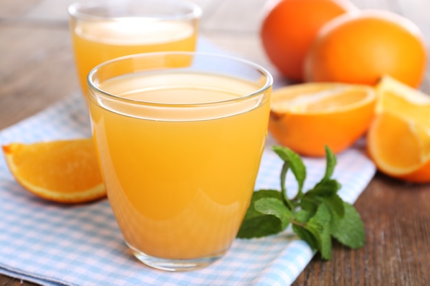 Gläser Orangensaft mit Orangen auf Holztisch schließen oben