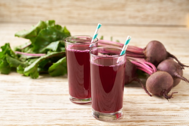 Gläser Rote-Bete-Saft mit Gemüse auf einem Holztisch. Frische Rote Bete und Saft