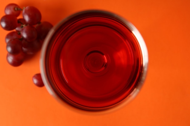 Gläser Rotwein und Traube auf orangem Hintergrund