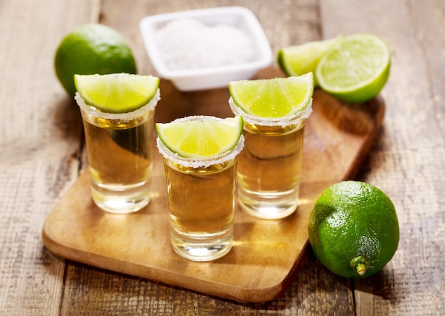 Gläser Tequila mit Limette auf Holztisch