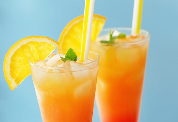 Gläser Tequila Sunrise Cocktail mit Orangenscheiben auf blauem Hintergrund in Nahaufnahme