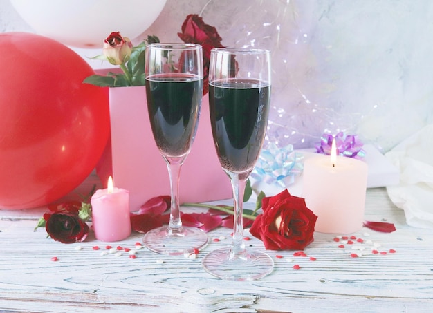 Gläser Wein, Geschenke, ein Strauß frischer Rosen, brennende Kerzen und Luftballons, alles Gute zum Geburtstag
