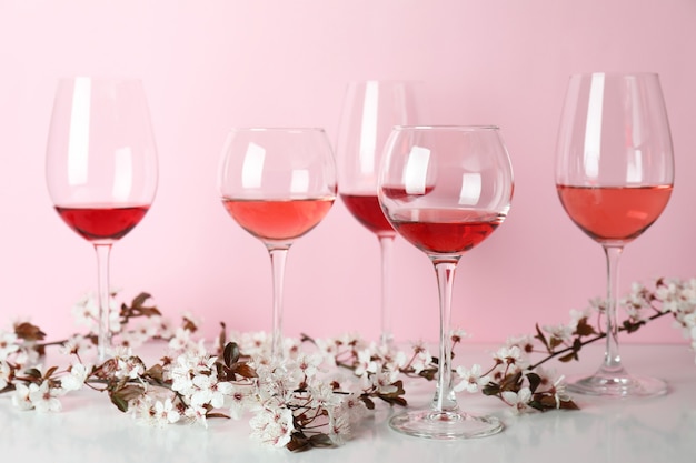 Gläser Wein und Kirschblüten vor rosa Hintergrund