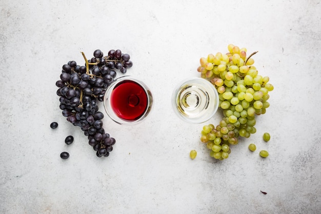 Gläser Weiß- und Rotwein mit reifen Trauben auf Steinhintergrund, Ansicht von oben