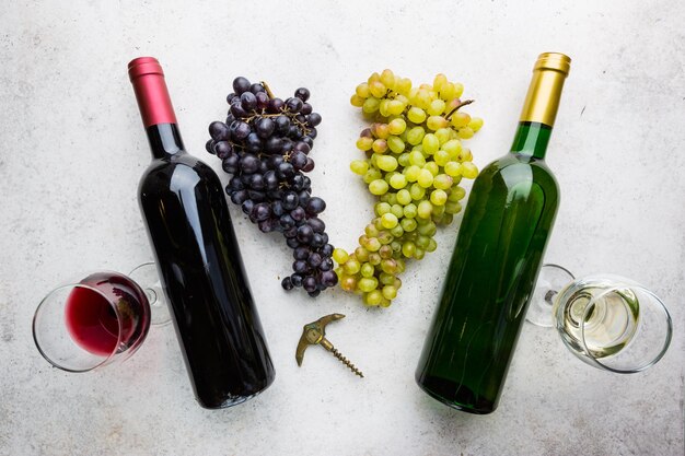 Gläser Weiß- und Rotwein mit reifen Trauben auf Steinhintergrund, Ansicht von oben