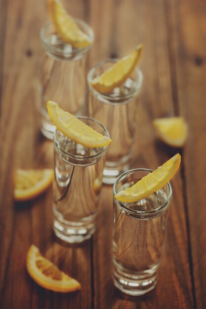 Gläser Wodka mit Zitrone auf hölzernem Hintergrund. Toning Bild.