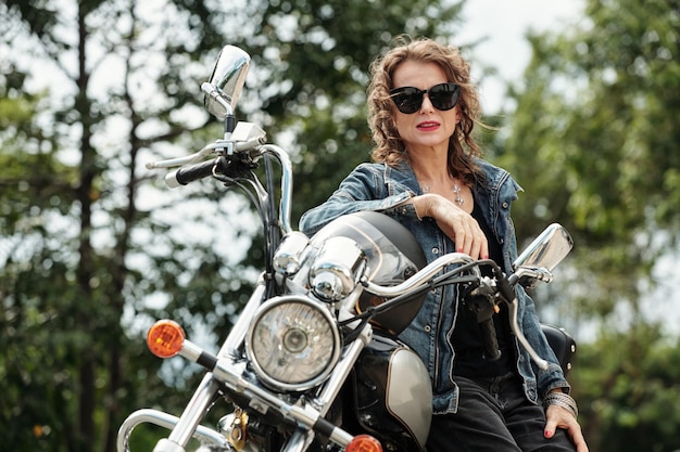 Glam Rock mujer de pie junto a la motocicleta