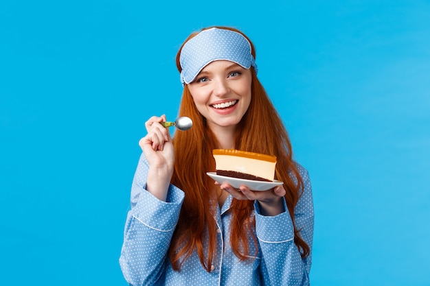 Glamour atraente ruiva mulher branca em nightweat, dormir máscara comer bolo delicioso