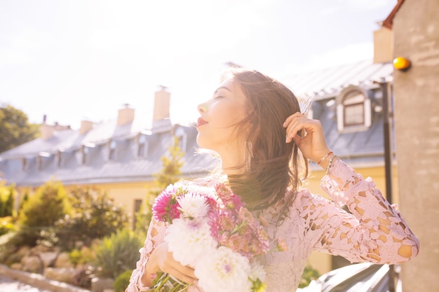 Glamour-brünette-modell mit einem blumenstrauß in sonnenstrahlen