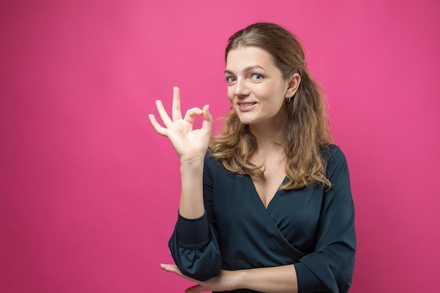 Glamour-Frau in einem dunkelblauen Kleid mit einem Schluck Kaffee auf rosa Hintergrund