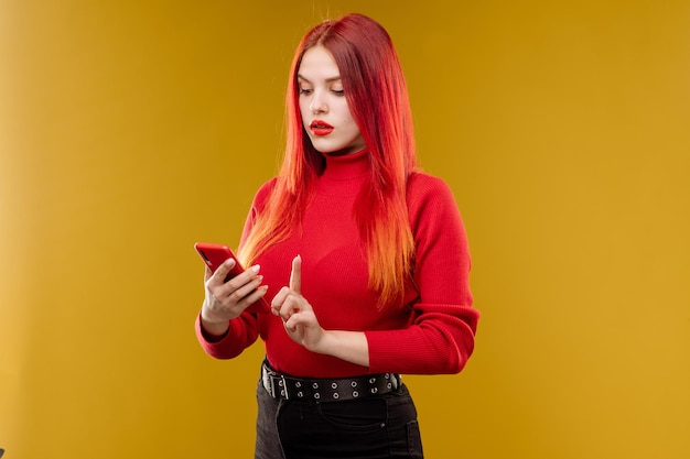 Glamour mulher com cabelo vermelho usando smartphone em fundo amarelo