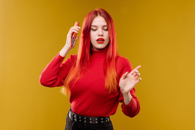 Glamour mulher com cabelo vermelho usando smartphone em fundo amarelo