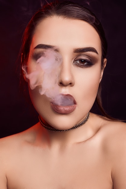 Glamour seductora hermosa mujer morena fumando cigarrillo electrónico