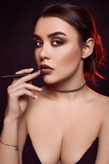 Glamour seductora hermosa mujer morena fumando cigarrillo electrónico