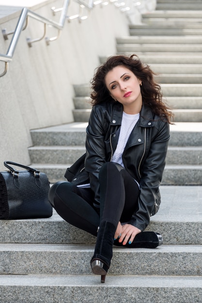 Foto glamouröse junge brünette frau in der schwarzen lederjacke, die auf der stadtstraße aufwirft und spaß hat