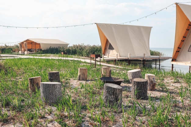 Foto glamping-zelt im wald. luxus-zelt-meerblick. natur grüner tourismus. amfeuerplatz holz im lager.