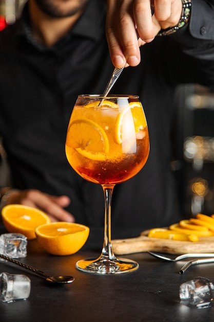 Glas Aperol-Spritz-Cocktail mit Orangenschalen-Spritz-Cocktail und auf dunklem Hintergrund