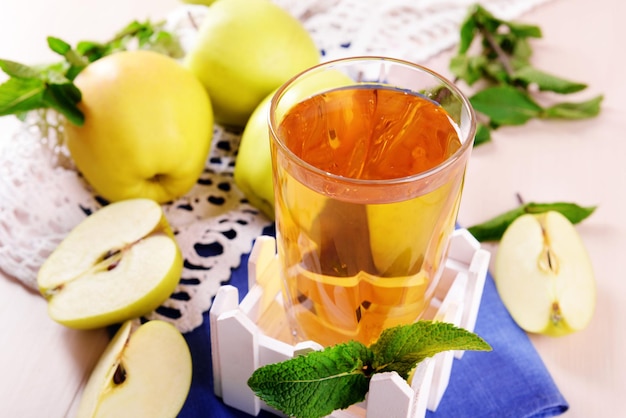 Glas Apfelsaft mit Früchten und frischer Minze auf Tisch hautnah