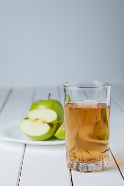 Glas Apfelsaft und Äpfel auf Holztisch, auf Naturhintergrund