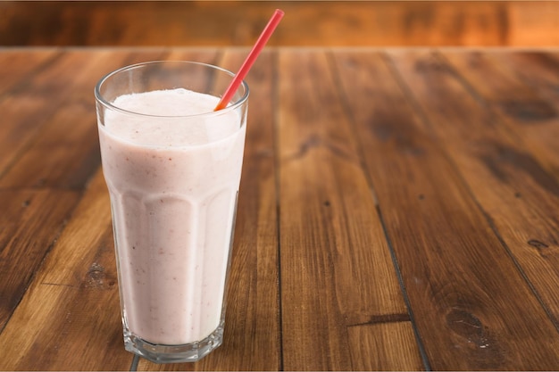 Glas auf frischem schmackhaftem Milchshake auf Holzhintergrund