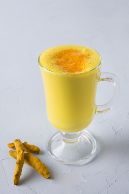 Glas ayurvedische goldene Gelbwurz Latte-Milch, Kurkumapulver auf Weiß.