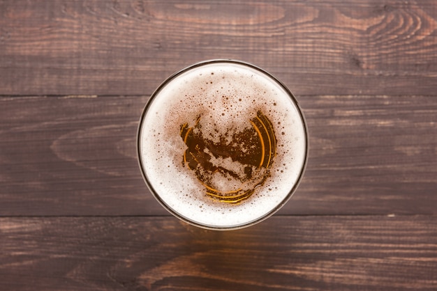 Glas Bier auf einem hölzernen Hintergrund. Ansicht von oben