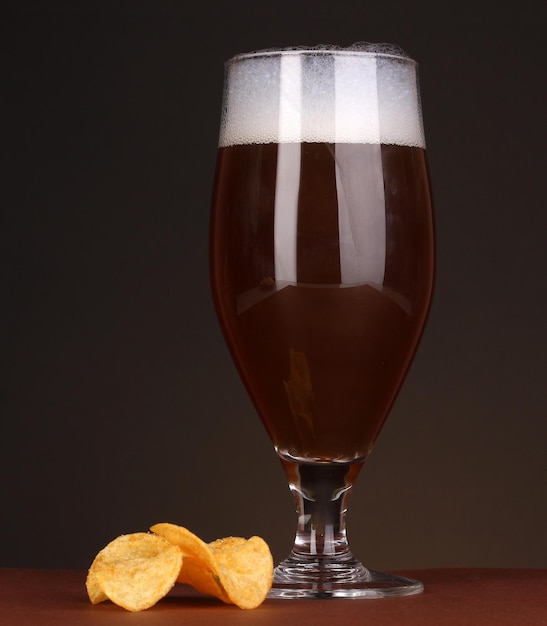 Glas Bier mit Chips auf braunem Hintergrund