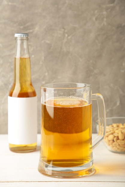 Glas Bier mit Erdnüssen auf grauem Hintergrund. Vertikales Foto