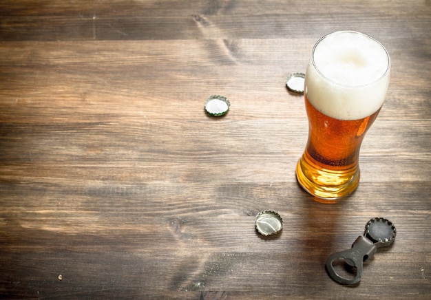 Glas Bier mit Stopfen und Flaschenöffner. Auf einem Holztisch.