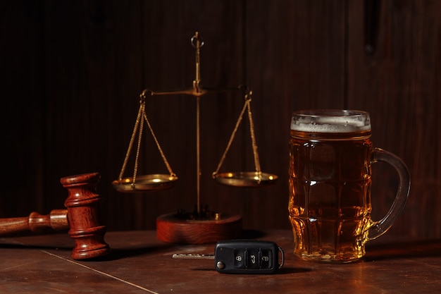 Glas Bierautoschlüssel und hölzerner Richterhammer in einem Notar-Alkohol- und Gesetzeskonzept