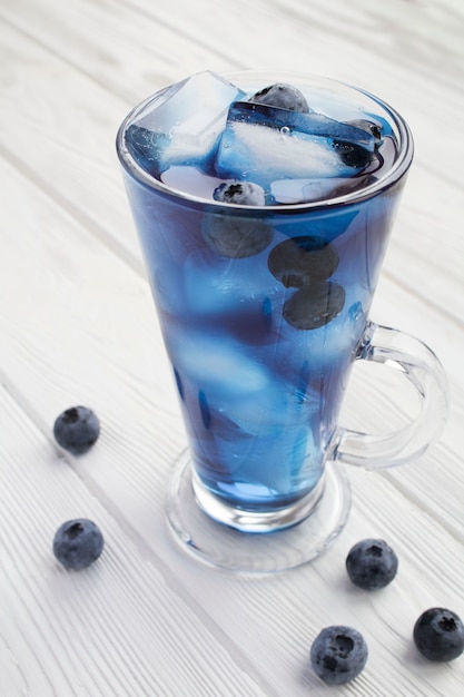 Glas blauer Cocktail mit Eiswürfeln und Heidelbeere