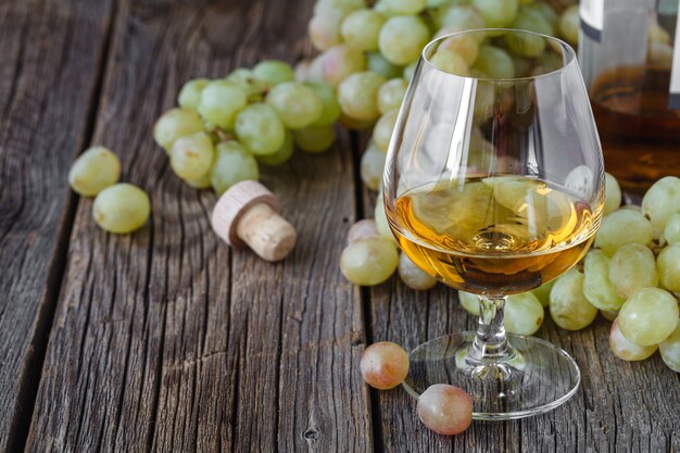 Glas Brandy mit Pinsel der Trauben auf dem Tisch, Erntefeiertag