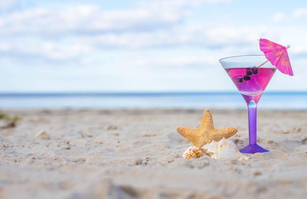 Glas Cocktail am Sandstrand und Seestern am Meer.Sommerferien, Urlaubskonzept.