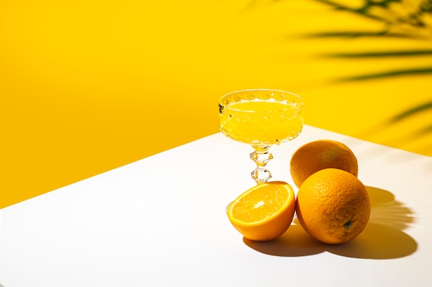 Glas Cocktail oder Orangensaft im Schatten einer Palme und Sonnenlicht.