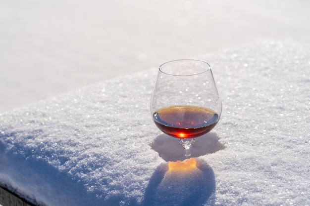 Glas Cognac auf einem Bett aus Schnee und weißem Hintergrund hautnah