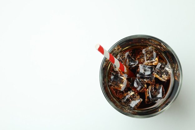 Glas Cola mit Eiswürfeln und Stroh auf weißer Oberfläche