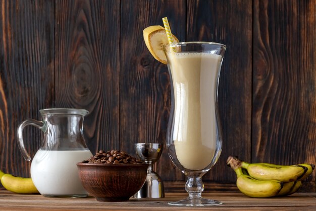 Glas Dirty Banana Cocktail mit Zutaten auf Holzwand