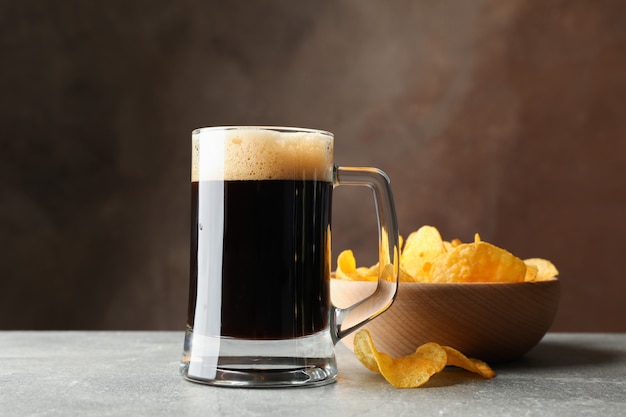 Glas dunkles Bier und Pommes auf grauem Tisch