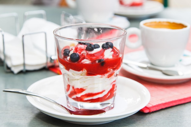 Glas Eisdessert mit Heidelbeeren und Sirup auf dem Cafétisch