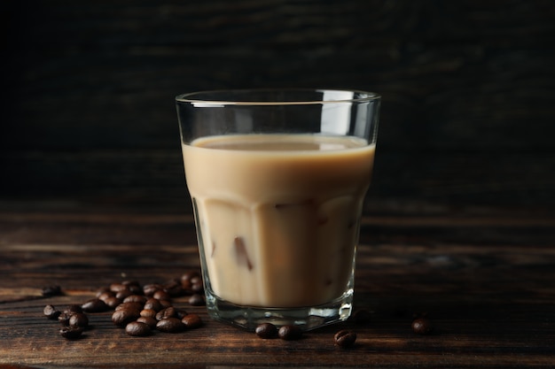 Glas Eiskaffee auf hölzernem Hintergrund. Kaffeesamen