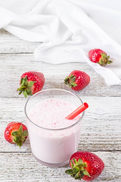 Glas Erdbeer-Smoothie mit Strohhalmen auf einem Holztisch.