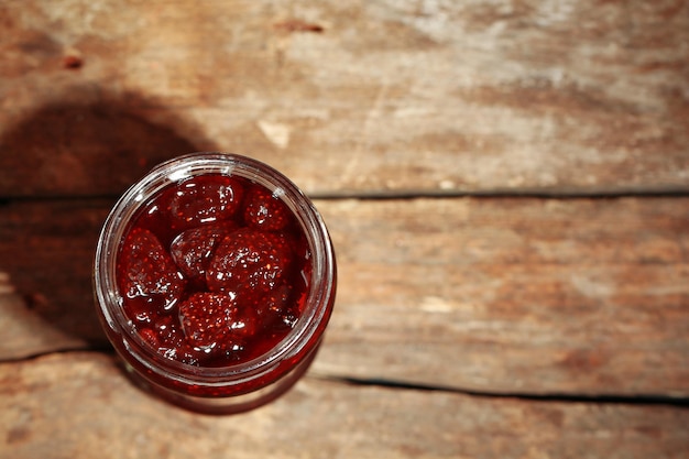 Glas Erdbeermarmelade auf Holzhintergrund