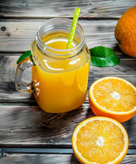 Glas frisch gepresster Orangensaft mit frischen Früchten im Hintergrund, ai generiert