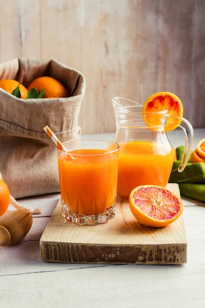 Glas frisch gepresster Orangensaft und Blutorangen auf Holztisch.