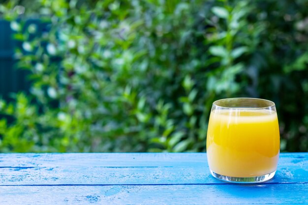 Glas frischer Orangensaft auf dem blauen Holztisch