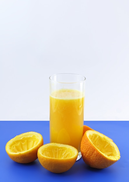 Glas frischer Orangensaft mit Quetschscheibe auf blauem Hintergrund..