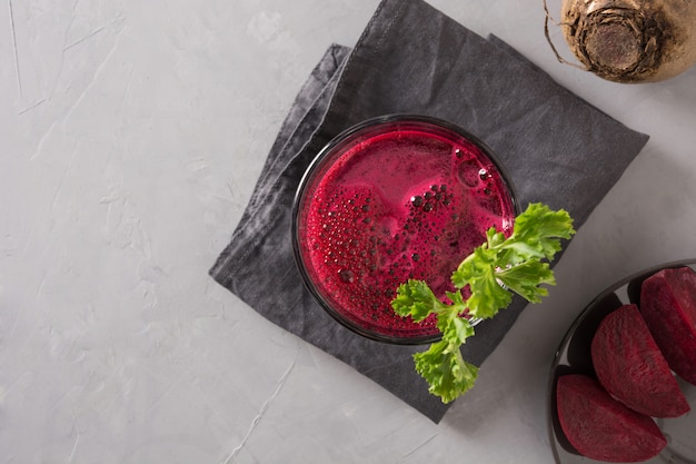 Glas frischer Rote-Bete-Wurzeln Saft schmücken Petersilie auf Grau.