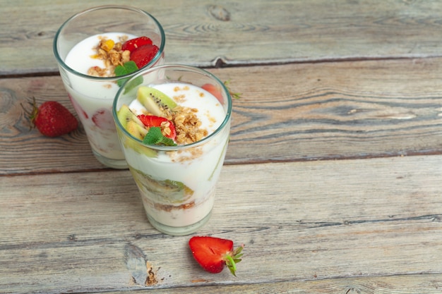 Glas gesunder Erdbeerjoghurt mit frischen Beeren auf Draufsicht des Holztischs