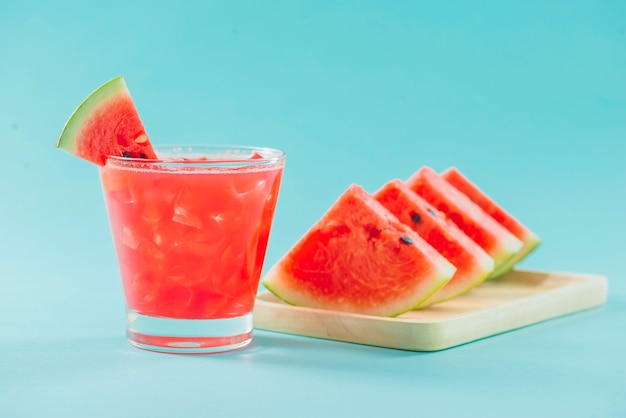 Glas gesunder Wassermelonensaft im Sommer auf blauem Hintergrund.