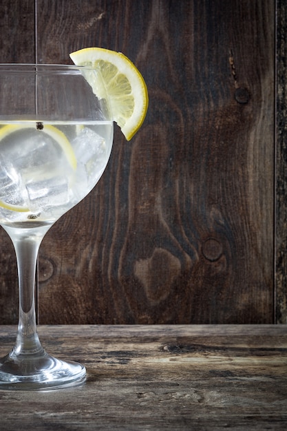 Glas Gin Tonic mit Zitrone auf Holz